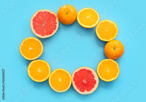 Frame made of fresh citrus fruits on color background