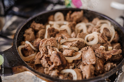 Fried veal liver with onions in a pan. Braised cow and pork liver