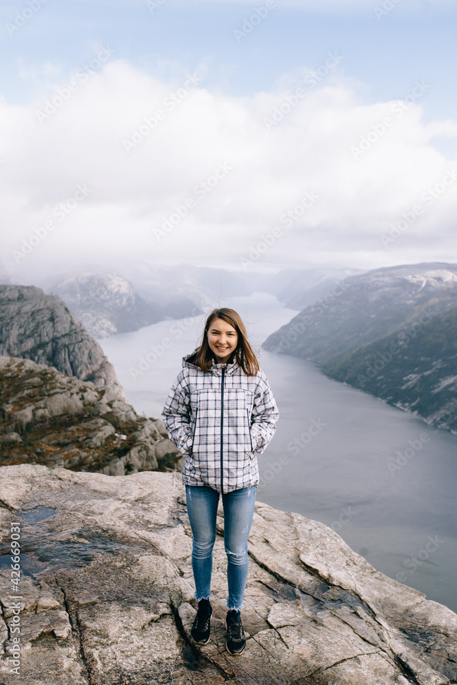 A pretty girl stands on top of Mount Preikestolen (Pulpit Rock) in Norway A pretty girl stands on top of Mount Preikestolen (Pulpit Rock) in Norway