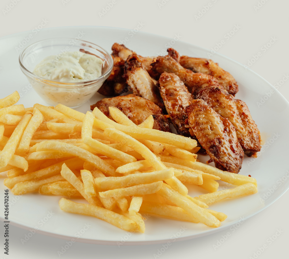 Chicken wings with french fries and garlic mayonnaise and sweet and sour sauce. Chicken wings with french fries and garlic mayonnaise and sweet and sour sauce.