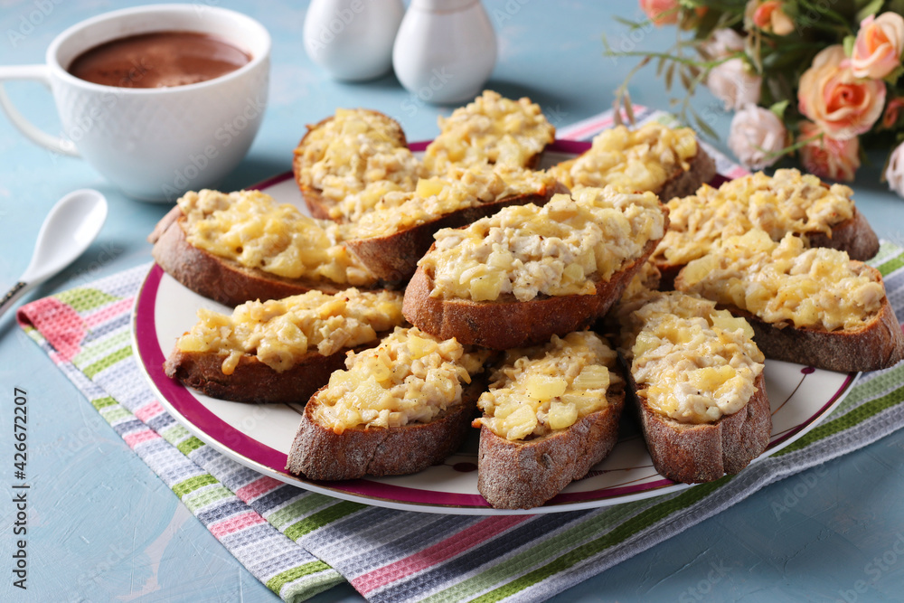 Baked homemade toasts with chicken, cheese, pineapple and garlic on a plate on light blue background. Baked homemade toasts with chicken, cheese, pineapple and garlic on a plate on light blue background.