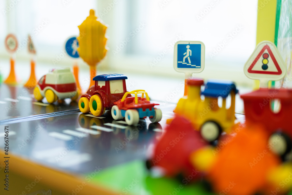 Obraz premium toy pedestrian crossing. multicolored little cars stand on the play road next to traffic lights, traffic signs
