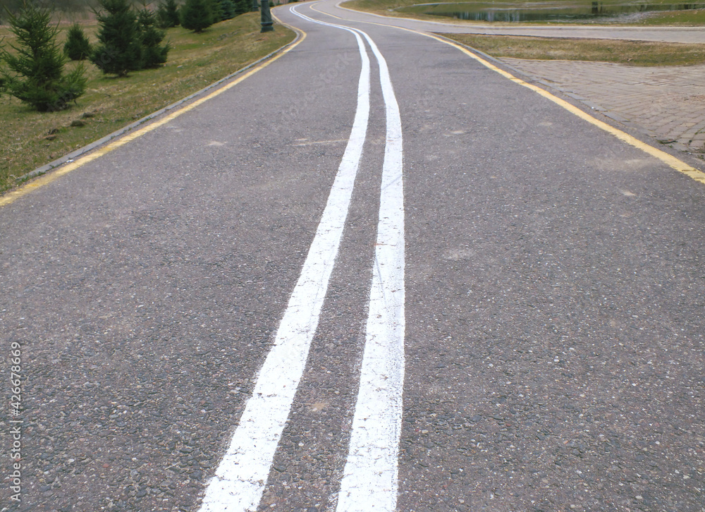 gray bike path in two directions, separated by two white parallel lines