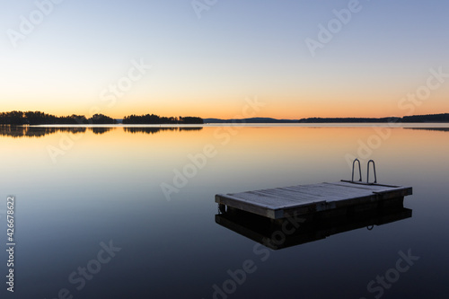 panorama of a wooden raft on calm lake water at sunrise or sunset