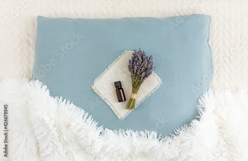 Using lavender flower essential oil for better good night sleep. Aromatherapy concept. Lavender oil and bouquet of dried lavender flowers on soft pillow in home bedroom.