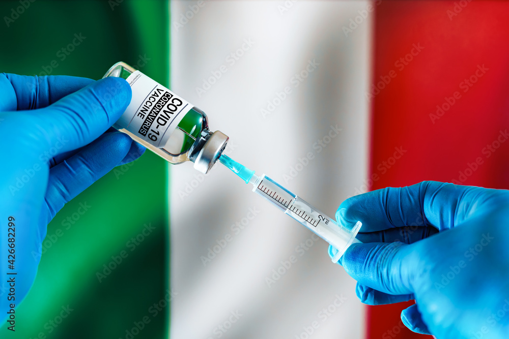 Injecting dose of vaccine in syringe for Covid-19 over the Italian flag. Preparing vial of medicament for the vaccination of Coronavirus cure In Italy Injecting dose of vaccine in syringe for Covid-19 over the Italian flag. Preparing vial of medicament for the vaccination of Coronavirus cure In Italy