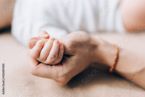 The hand of the newborn baby is held by the hand of the mother. Caring for newborn children. The child learns the world through touch