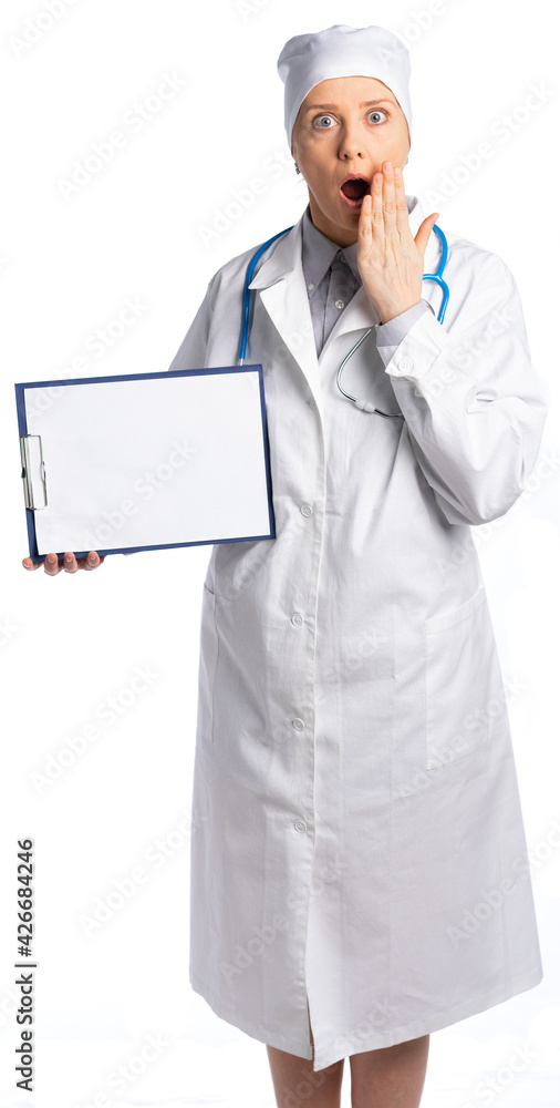 female doctor in a white coat and hat. doctor holds a pill with a white sheet of paper. The specialist looks at us in dismay, covered her mouth with her hand. space for inscription isolated female doctor in a white coat and hat. doctor holds a pill with a white sheet of paper. The specialist looks at us in dismay, covered her mouth with her hand. space for inscription isolated