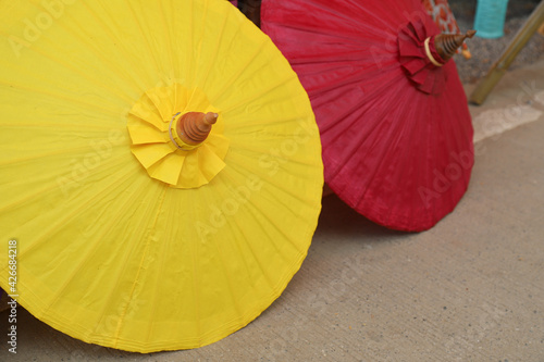 Closeup of yellow handmade paper umbrella on the ground.