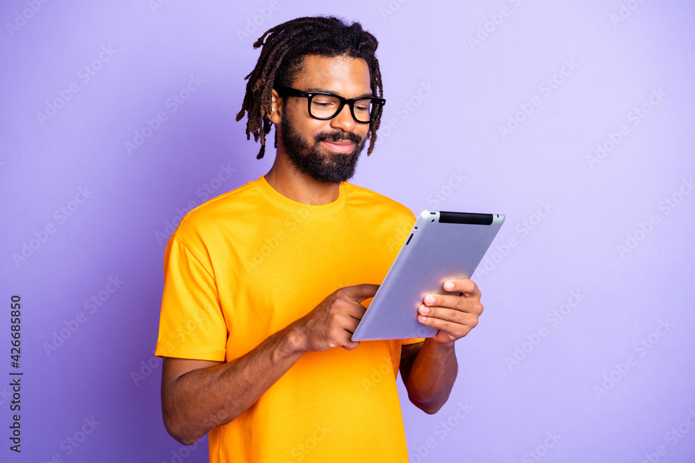 Portrait of nice optimistic brunet guy type tablet wear spectacles orange  t-shirt isolated on vibrant lilac color background Stock Photo | Adobe Stock