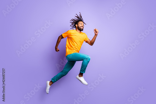 Full size profile photo of nice optimistic brunet guy jump run wear t-shirt pants isolated on lilac color background