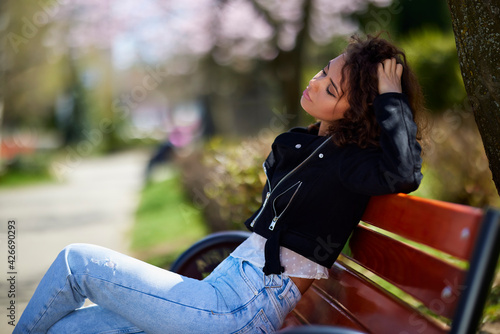 Portrait of a woman sitting on a bench in the park on a beautiful spring day. © czamfir