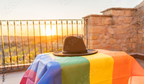 Rainbow gay pride flag on table with a black hat at sunset.Beautiful creative shot of LGBT movement flag