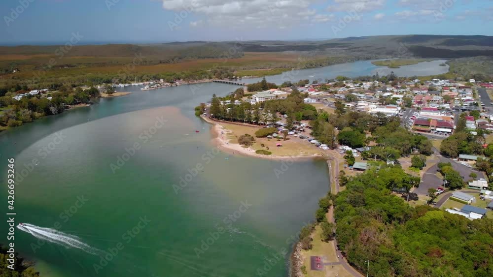 Aerial view overlooking a boat on a river, at the Evans Head village, New South Wales, Australia - reverse, drone shot Aerial view overlooking a boat on a river, at the Evans Head village, New South Wales, Australia - reverse, drone shot