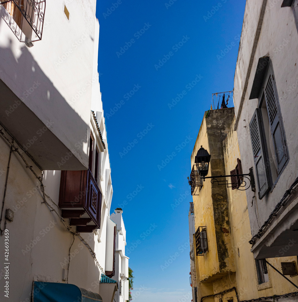Narrow street lined by apartments looking up into the blue sky in Tangier, Morocco