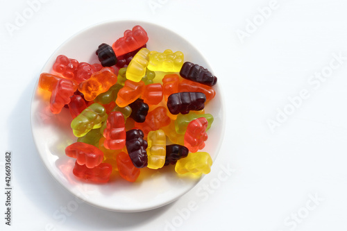 Multicolored gummy bears in bowl on white background. Top view, copy space. Flat lay food. Chewing gummies on plate