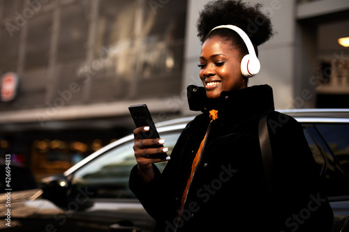 Young african woman outdoors. Beautiful woman listening to music while walking through the city