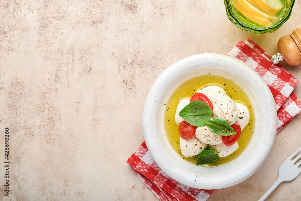 Caprese salad. Mozzarella cheese with basil and cherry tomato in white ceramic plate and tomato cherry on slate stone table background, copy space. Mock up. Caprese salad. Mozzarella cheese with basil and cherry tomato in white ceramic plate and tomato cherry on slate stone table background, copy space. Mock up.