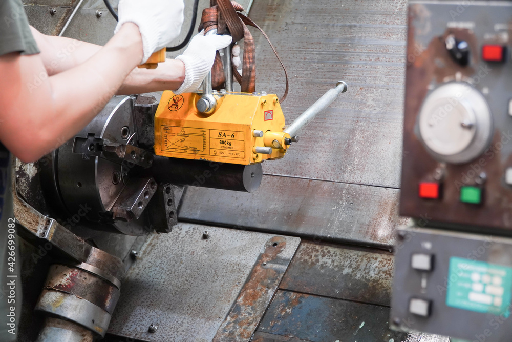 mechanic uses a magnet to lift the workpiece controlled by hand. mechanic uses a magnet to lift the workpiece controlled by hand.