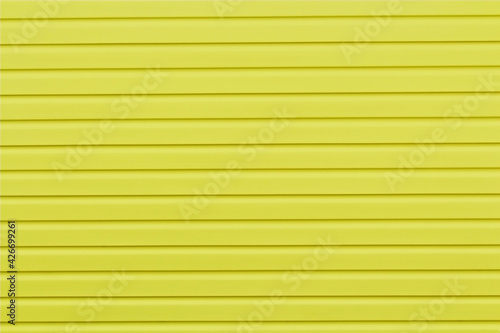 The wall of the house is finished with yellow siding.