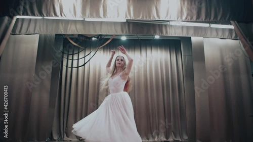Ballerina dancer on stage with her hair down spinning in place. Slow motion.