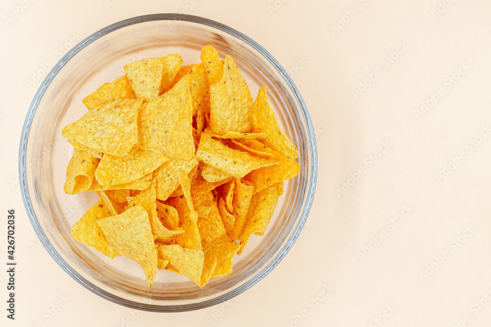 Corn chips into a glass bowl, nachos isolated on orange background with copy space ,Top view Corn chips into a glass bowl, nachos isolated on orange background with copy space ,Top view
