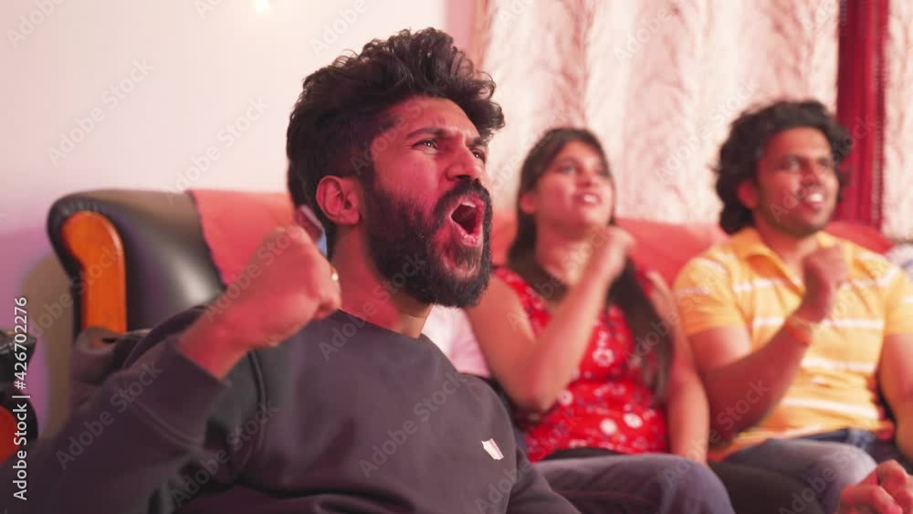 Close up of young man shouting and cheering up by saying player name of his supporting team while watching sports on tv with his friends at home. Close up of young man shouting and cheering up by saying player name of his supporting team while watching sports on tv with his friends at home.