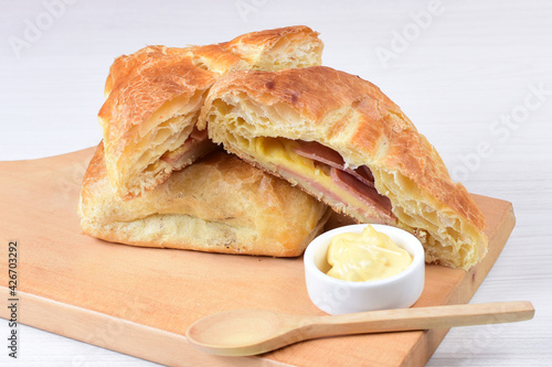 Puff pastry with ham and cheese displayed on white wooden background