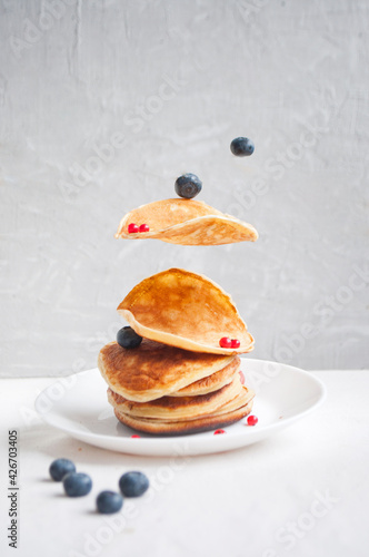 Flying freshly cooked pancakes and berries with honey, walnut for breakfast. Equilibrium floating food concept.