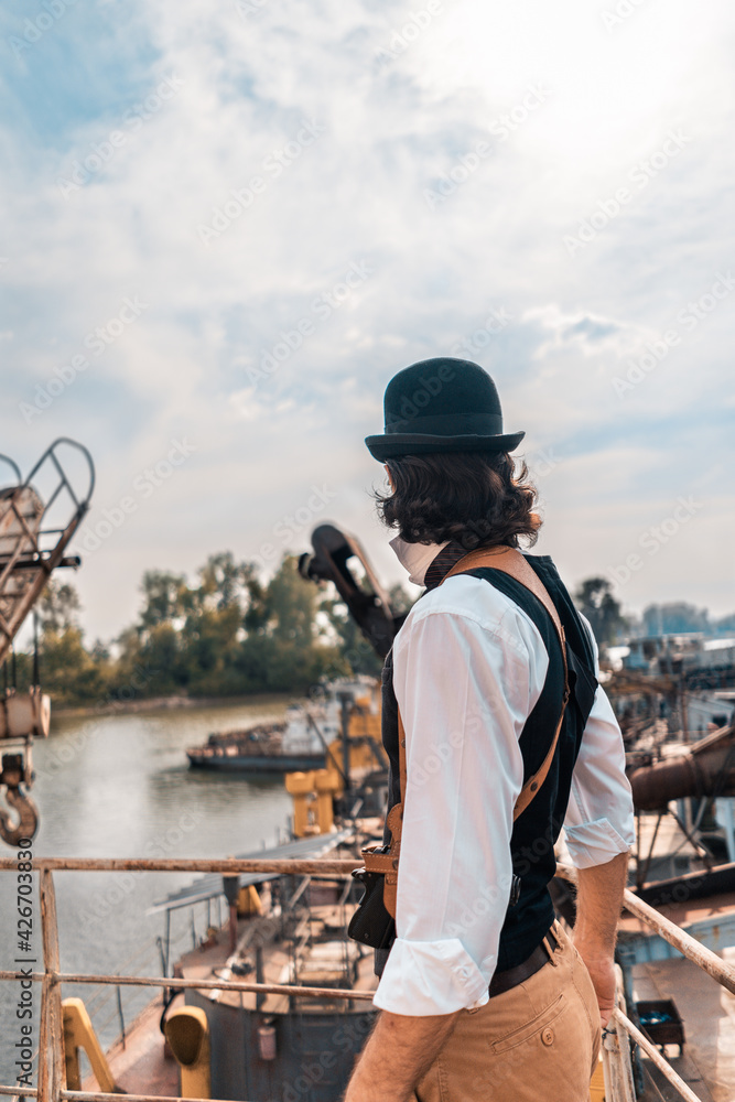Steampunk. A hero on a river barge surrounded by steel mechanisms. A man with a weapon. Steampunk. A hero on a river barge surrounded by steel mechanisms. A man with a weapon.