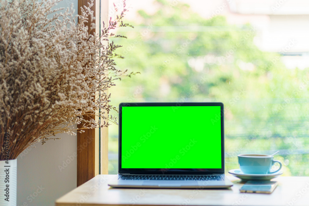 Mockup of laptop computer with empty screen with coffee cup and smartphone on table of the coffee shop background,Green screen Mockup of laptop computer with empty screen with coffee cup and smartphone on table of the coffee shop background,Green screen