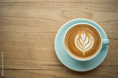 Hot coffee latte with latte art milk foam in cup mug on wood desk on top view. As breakfast In a coffee shop at the cafe,during business work concept