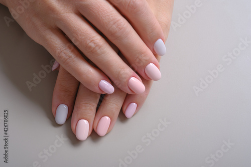  Hands with French manicure. Close Up Of Woman Fingers With Nail Art. Hands with pink and blue nail polish on a gray background. Selective focus