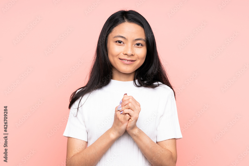 Teenager Chinese woman isolated on pink background laughing