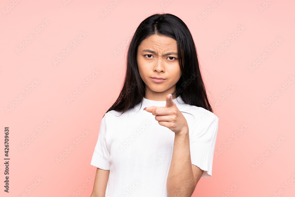 Teenager Chinese woman isolated on pink background frustrated and pointing to the front Teenager Chinese woman isolated on pink background frustrated and pointing to the front