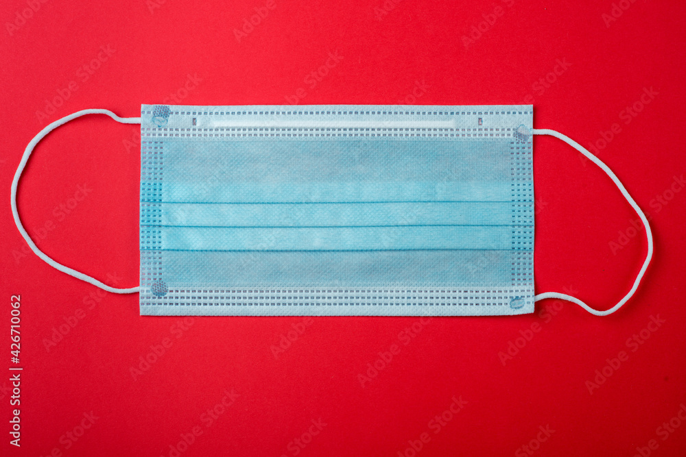 Surgical mask with rubber ear straps. Typical 3-ply surgical mask to cover the mouth and nose. Procedure mask from bacteria. Protection concept. Surgical mask with rubber ear straps. Typical 3-ply surgical mask to cover the mouth and nose. Procedure mask from bacteria. Protection concept.