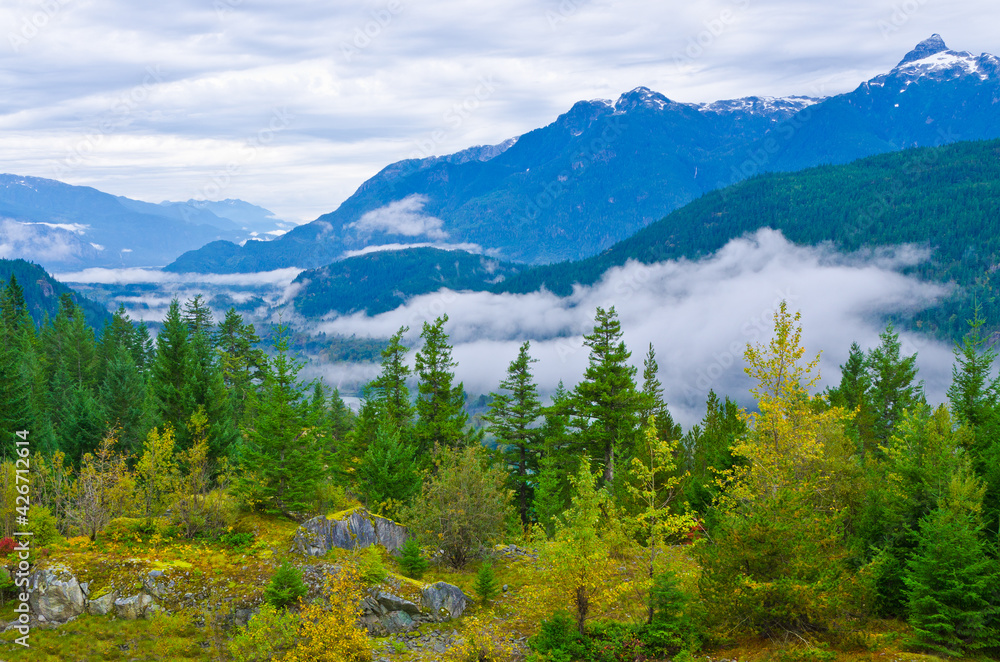 A beautiful view with cloudy sky with foggy mist around the mountains and trees in a beautiful and peaceful rural country scene.