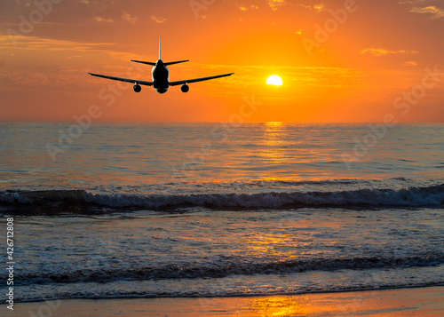 Sunset or sunrise (dawn, dusk ) flight of the airplane (jet) over beautiful sky and ocean.