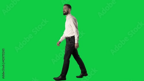 Amazed and fascinated young business man looking around walking in shop. Full body on green screen chroma key background.
