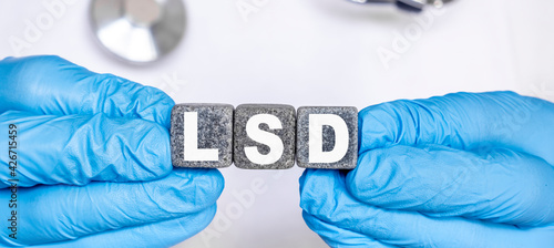 LSD Lysergic acid diethylamide - word from stone blocks with letters holding by a doctor's hands in medical protective gloves