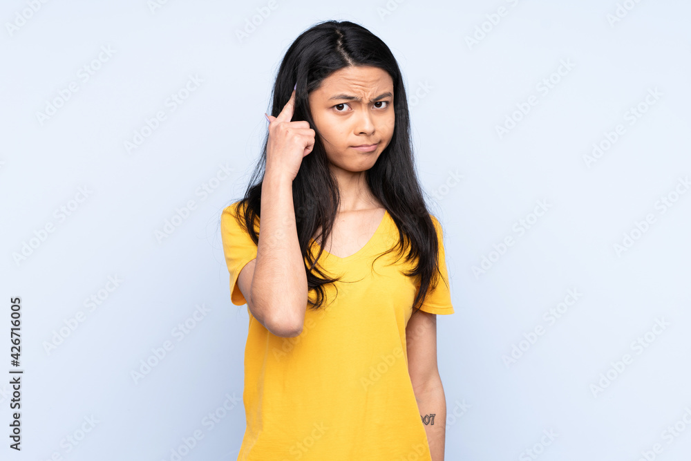 Teenager Chinese woman isolated on blue background thinking an idea Teenager Chinese woman isolated on blue background thinking an idea