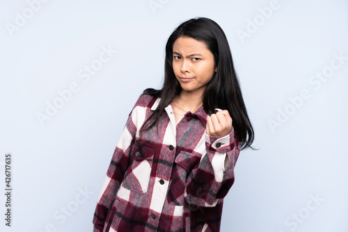 Teenager Chinese woman isolated on blue background with unhappy expression