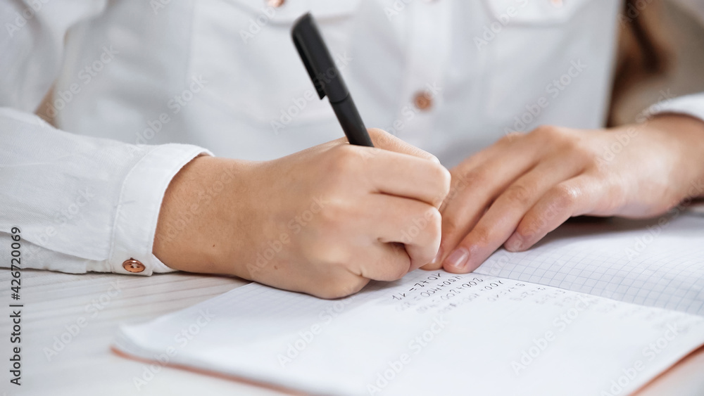 Cropped view of kid writing on notebook during homework. Cropped view of kid writing on notebook during homework.