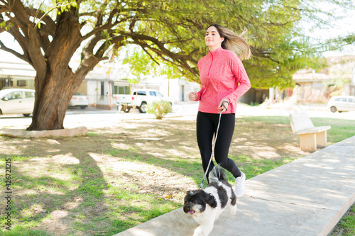Fit young woman running with her adorable dog photo