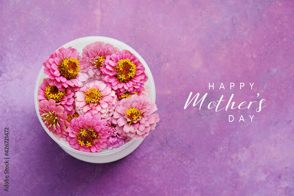 Naklejka premium Top view of zinnia flowers on purple background with Happy Mothers day text for holiday decorative banner.