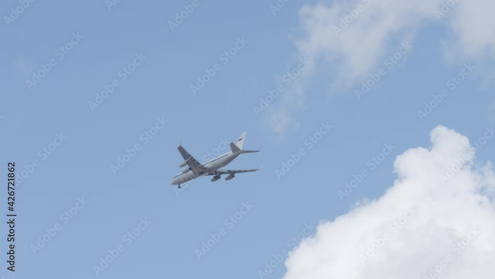 Big airliner with Russian flag on the tail descends for landing on cloudy sky background, telephoto lens shot on Red