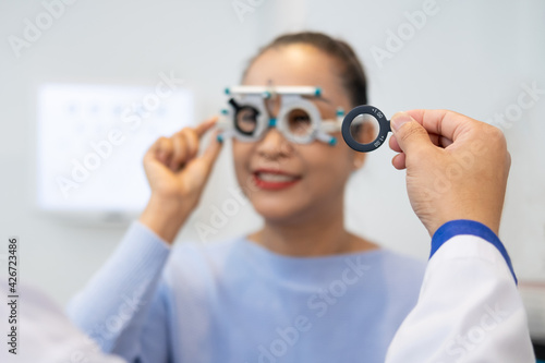 Selective focus at women face. While doctor using Optometry equipment and trial glasses frame to examine eye visual system of elder patient women with professional machine and technic.