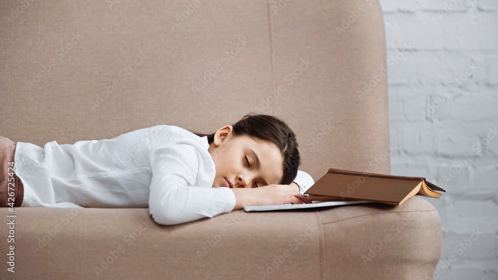 Girl sleeping on couch near book and notebook. Girl sleeping on couch near book and notebook.
