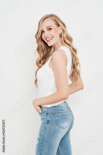 Sexy young blonde girl wearing jeans and a white shirt without sleeves smiling to camera