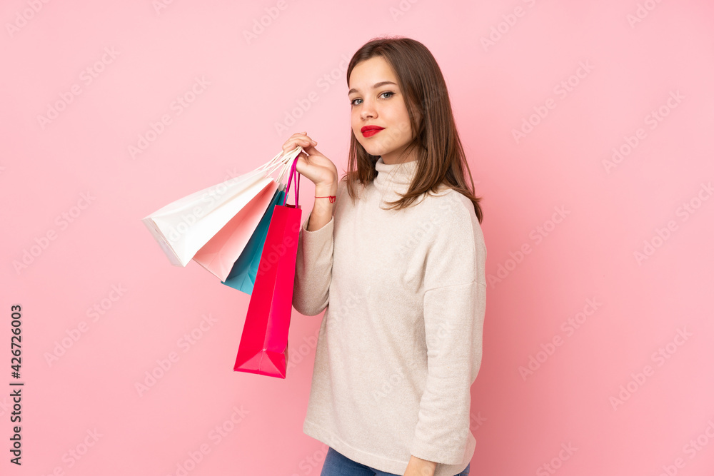 Teenager girl isolated on pink background holding shopping bags and smiling Teenager girl isolated on pink background holding shopping bags and smiling